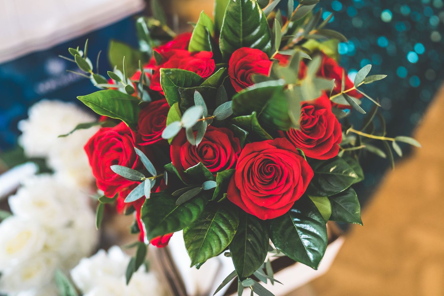Red roses and white floral bouquets arranged with greenery for a wedding celebration.