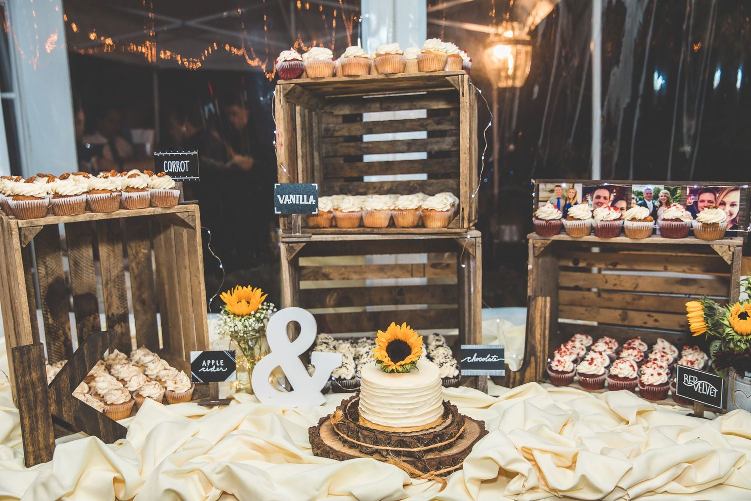 Rustic wedding dessert table with string lights, wooden decor and treats.