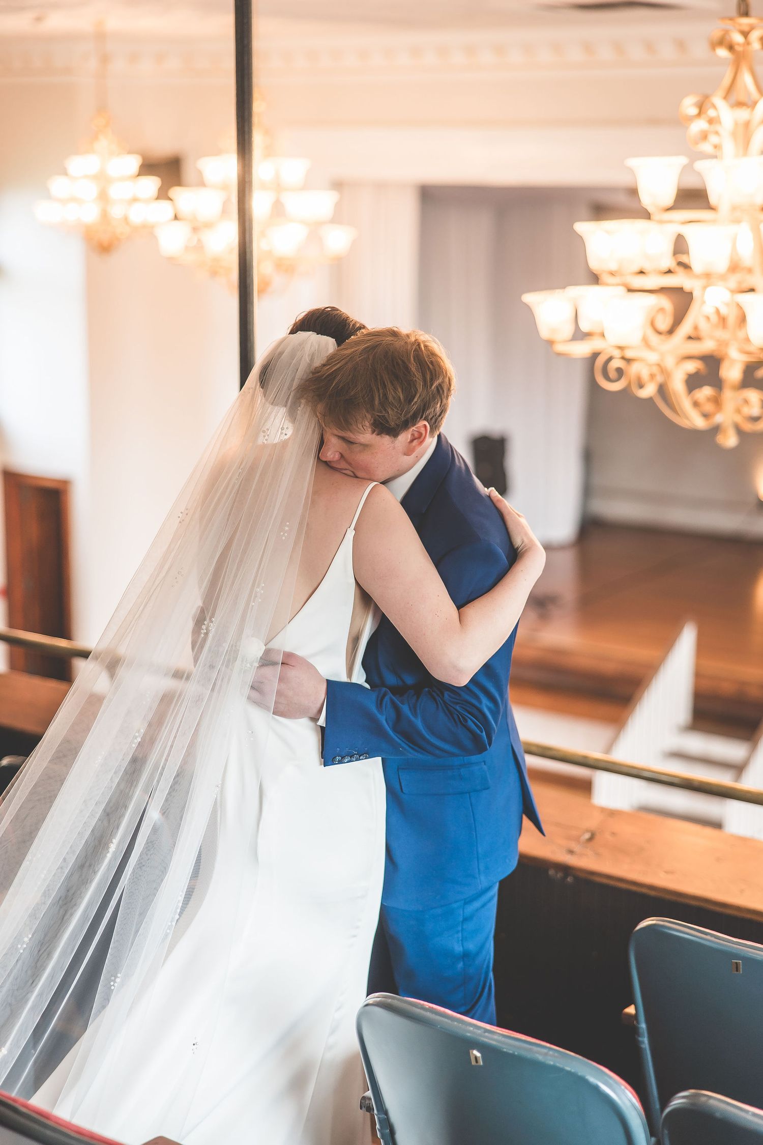 Emotional first look moment between two people in a wedding venue with warm lighting.