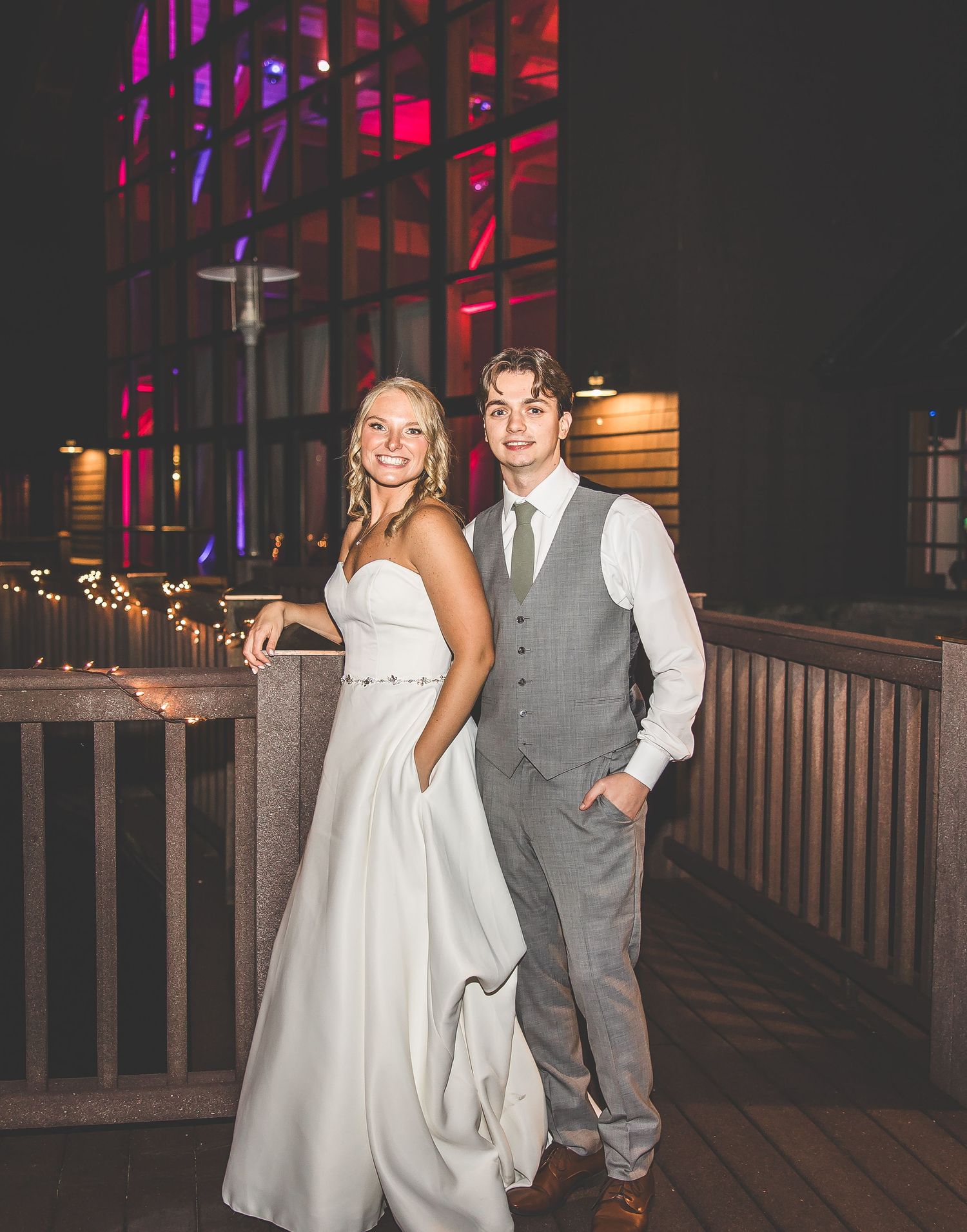 Couple dancing together at a wedding reception with colorful purple and red lighting in the background.