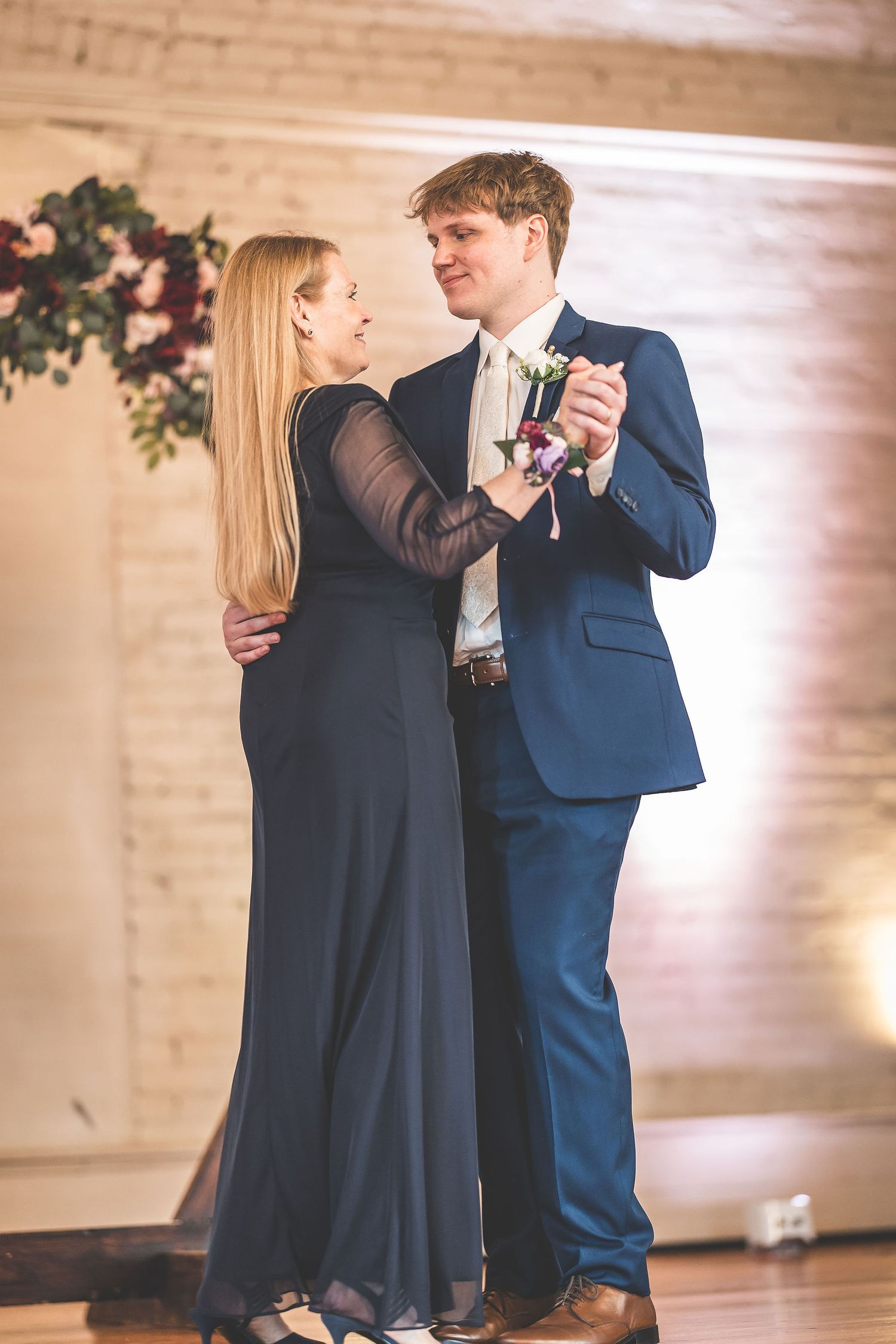 A romantic dance moment captured beneath warm lighting at an indoor venue.