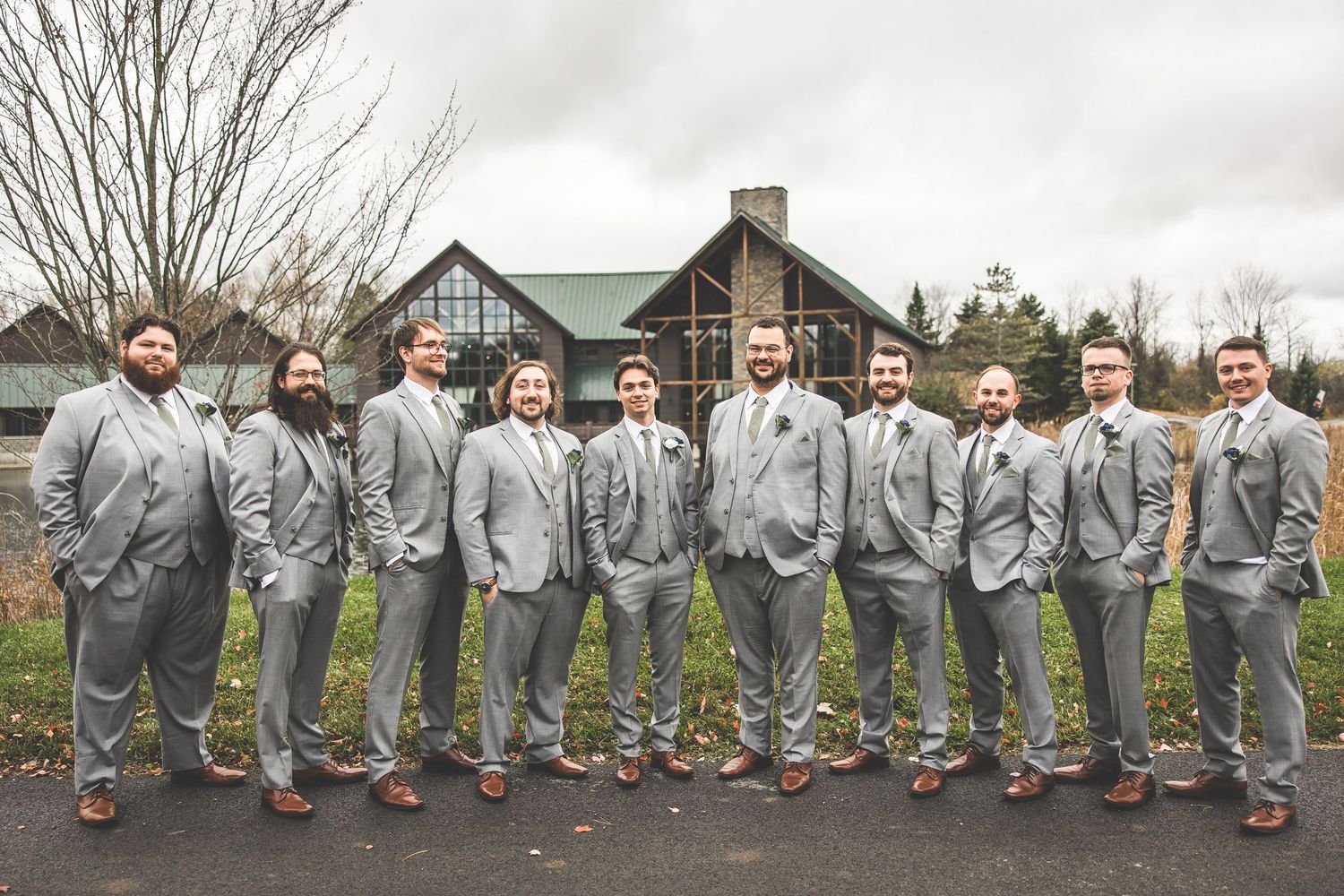 Groomsmen in matching gray suits and brown shoes line up for fun wedding photo.