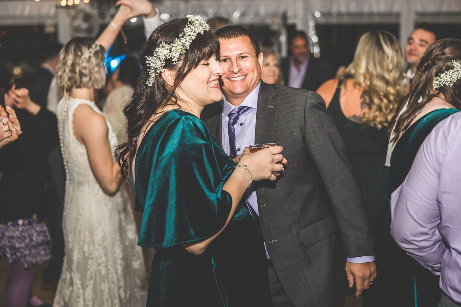 Guests enjoying themselves at an indoor wedding reception with decorative string lights.