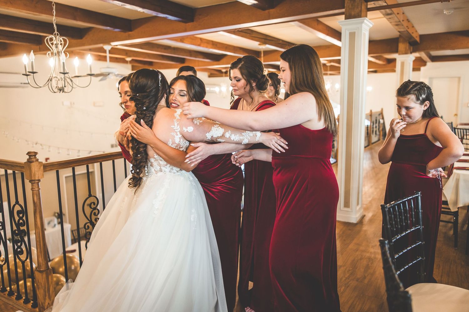Wedding party dancing and celebrating in a rustic reception hall with wooden beams.