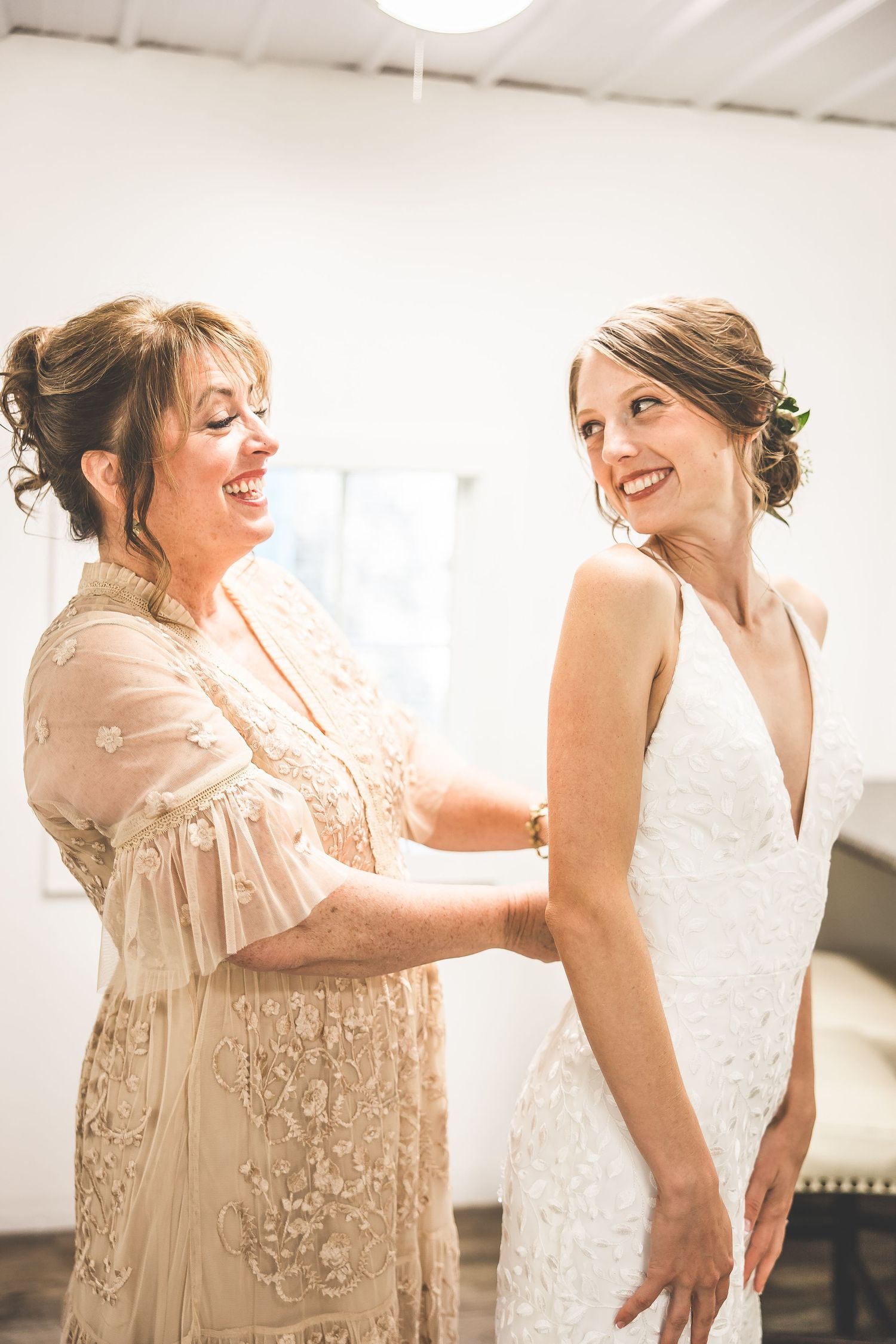 Two people in contrasting dresses share animated expressions during a candid moment.