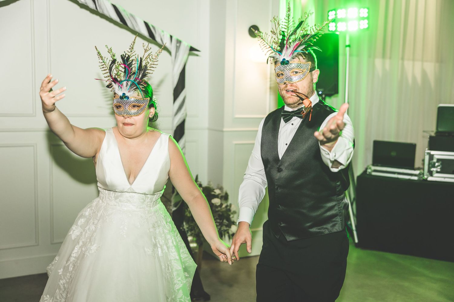 Wedding celebration with guests dancing and having fun under green ambient lighting.