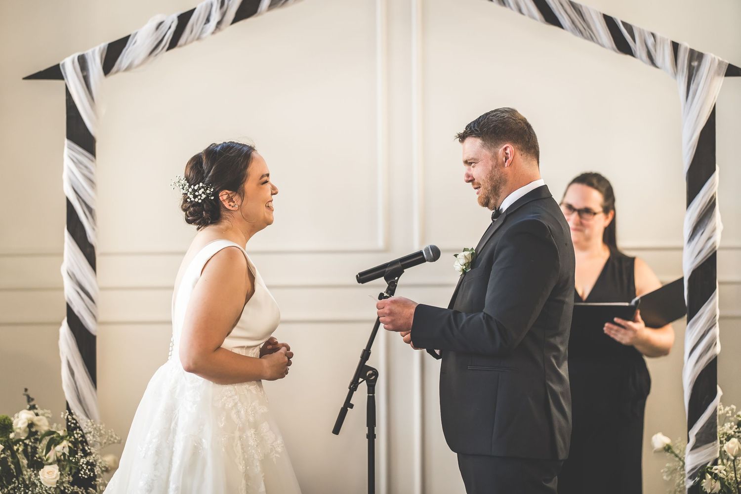 Wedding ceremony exchange with black and white decor elements in an elegant white room.