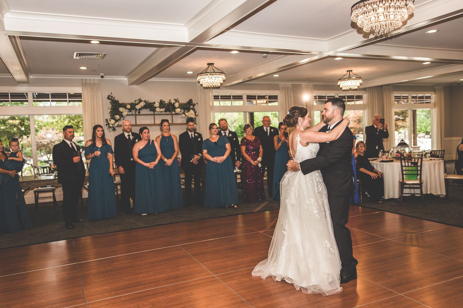 Wide view of an elegant wedding reception venue with chandeliers and dancing guests.