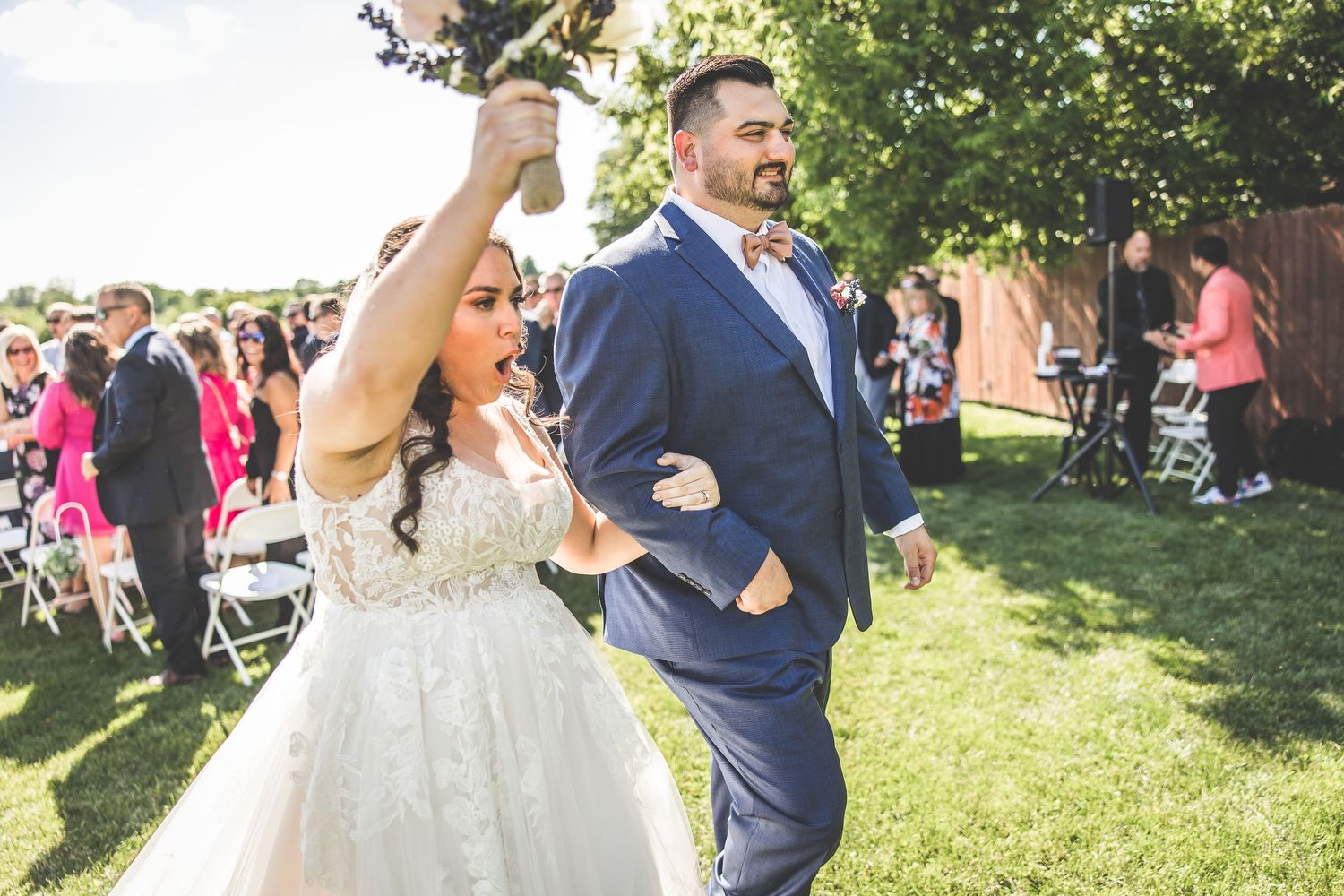 Wedding celebration on grassy lawn with guests enjoying festivities under blue skies.