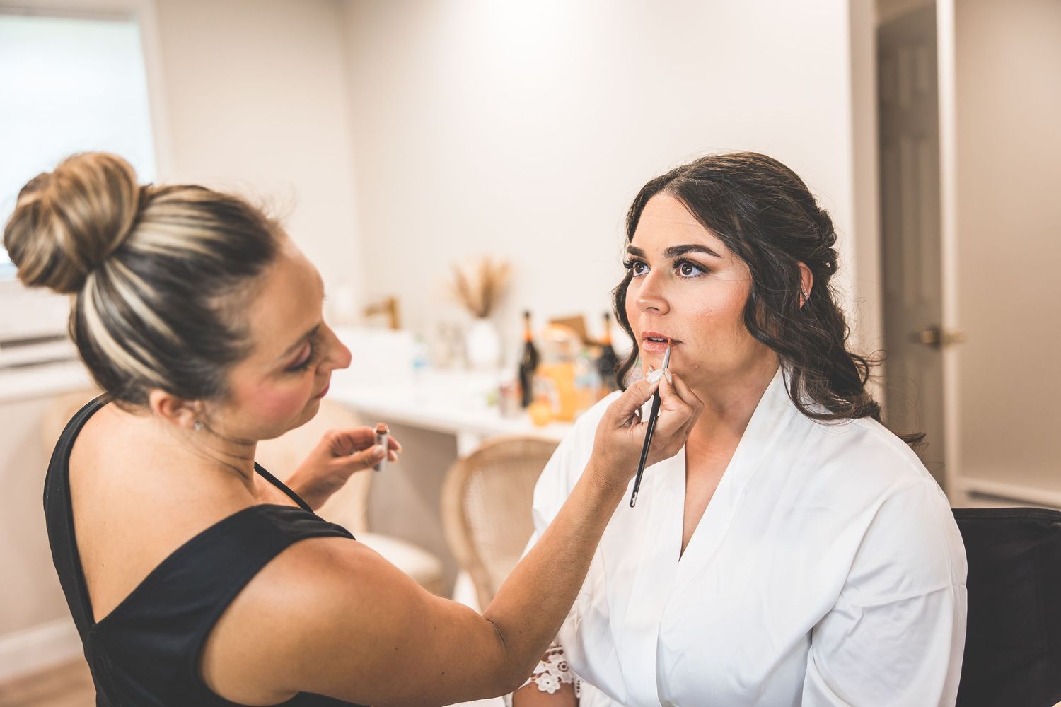 People getting ready in a bridal suite with makeup being applied.