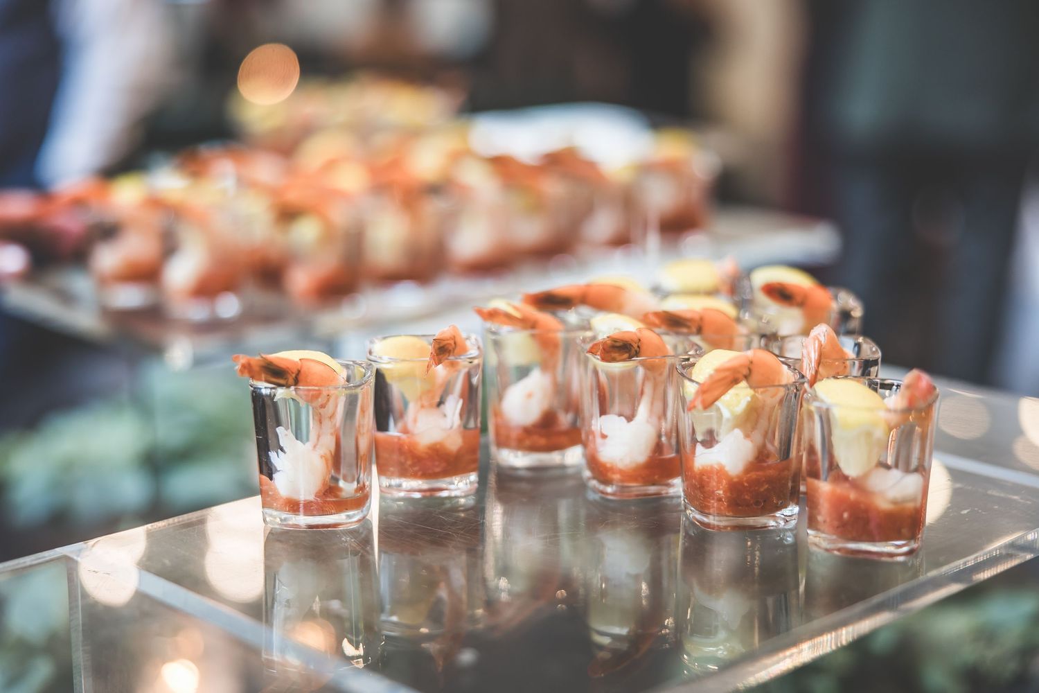 Row of elegant appetizer shooters arranged on silver tray for wedding cocktail hour.