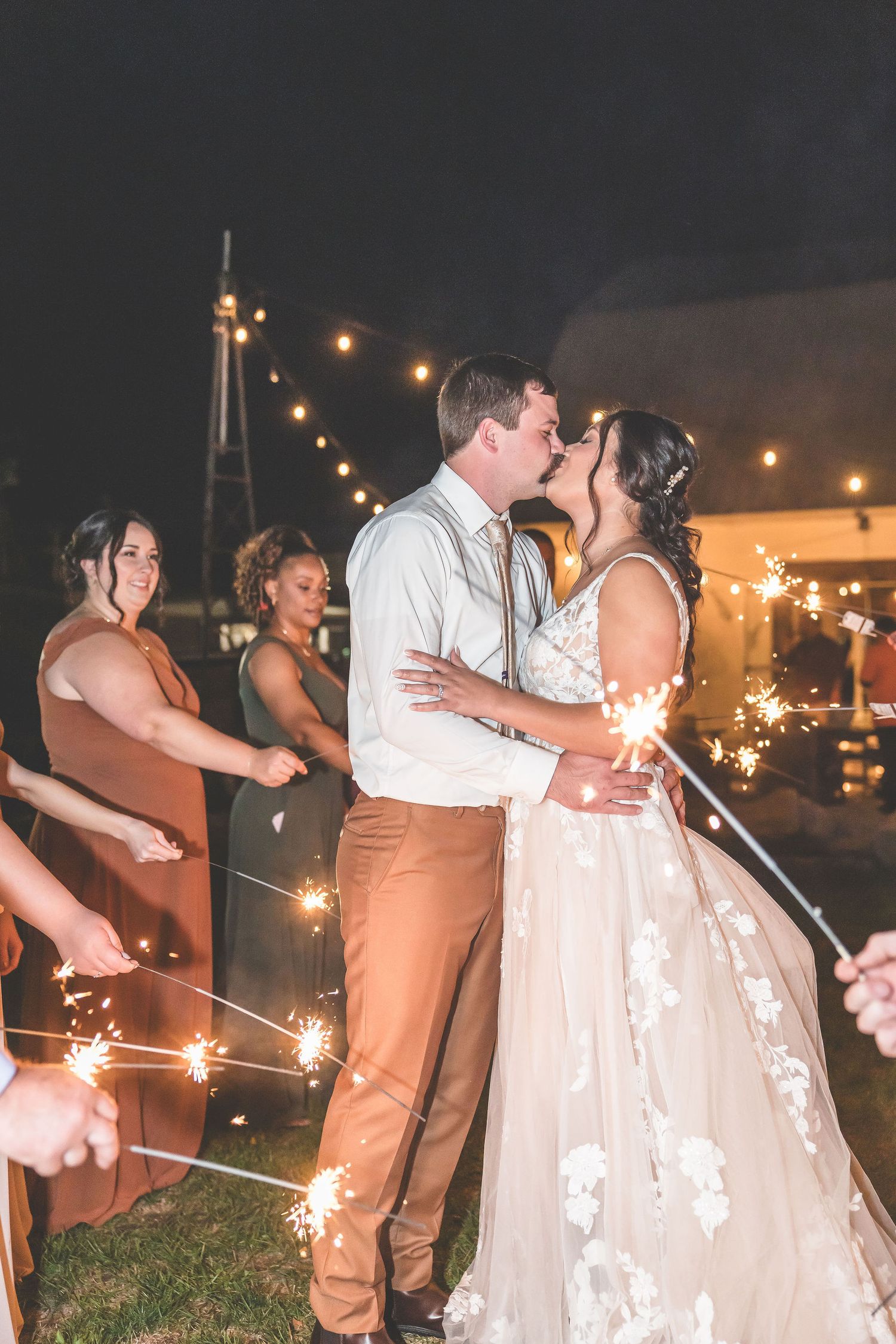 Romantic sparkler exit with couples lining the pathway at a nighttime wedding celebration.