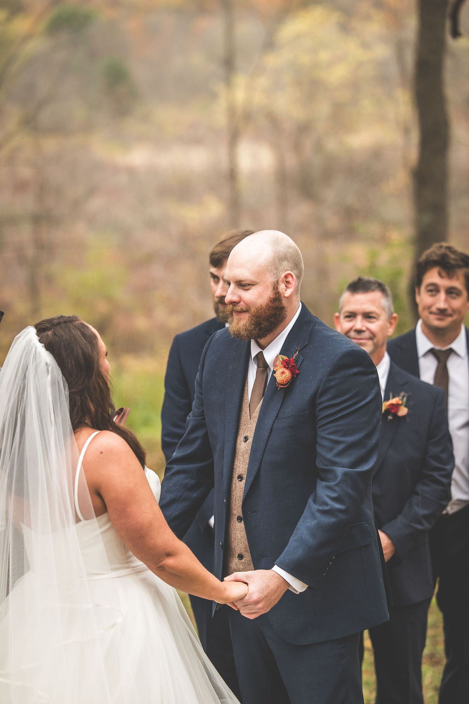 Intimate wedding ceremony moment with couple exchanging vows in a wooded setting.