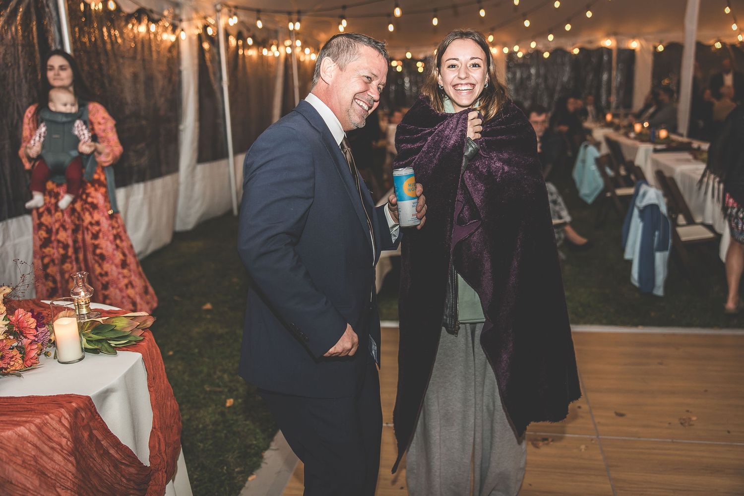 Couples dancing together during a festive wedding reception under glowing string lights.