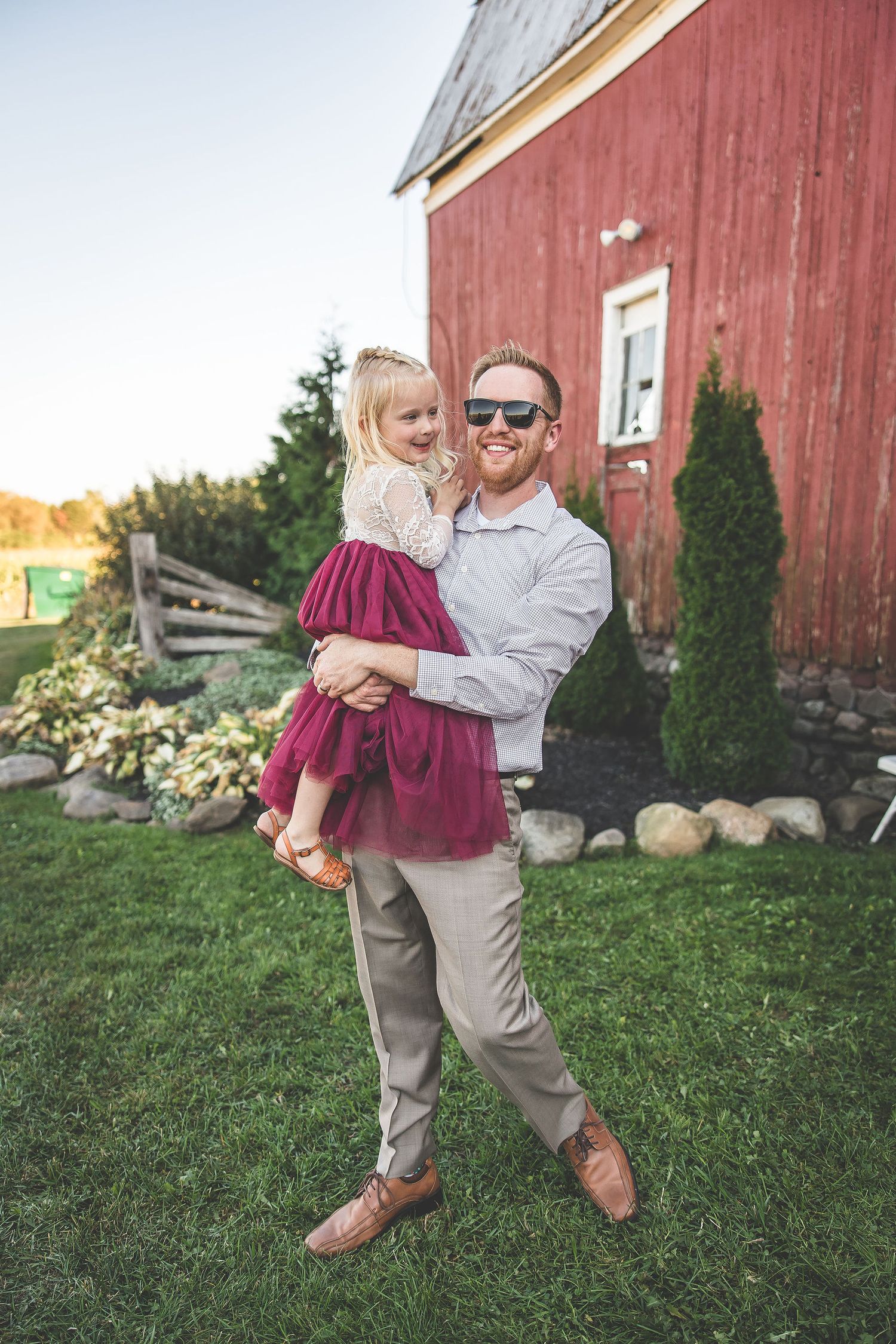 A romantic dance sequence in front of a red barn with a couple in formal attire twirling in the grass.