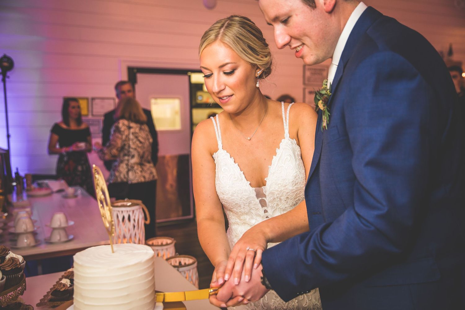 Newlyweds cutting their wedding cake together at the reception.