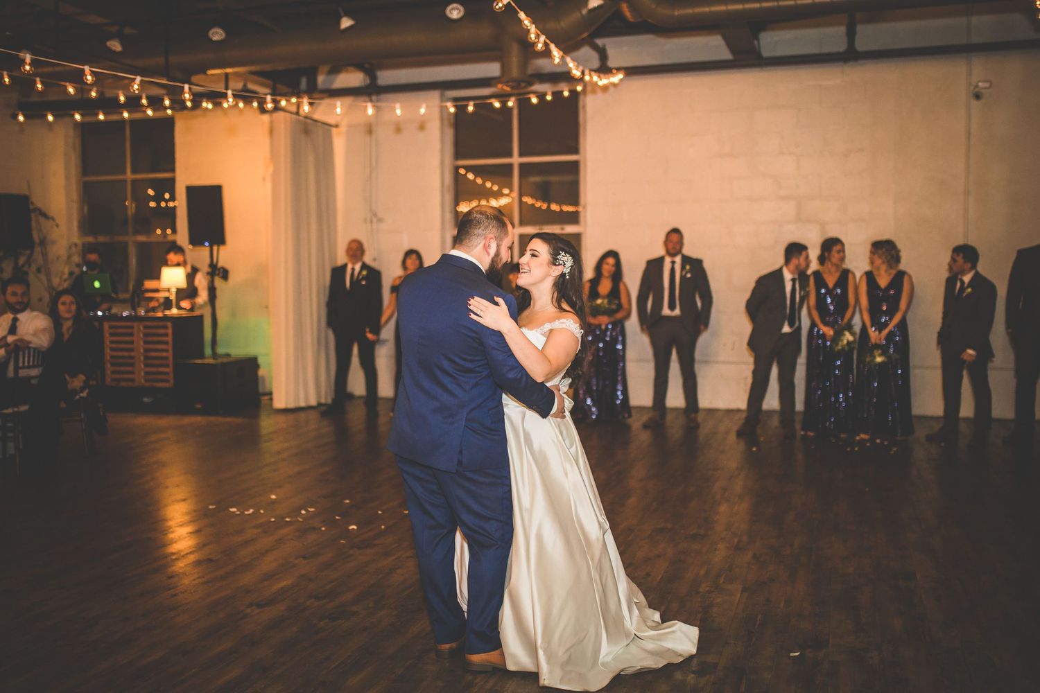 A wedding reception dance floor with string lights illuminating a spacious venue.