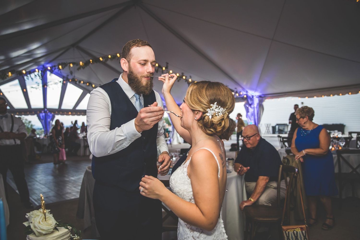 Couples dancing together under a white tent with string lights at a wedding reception.