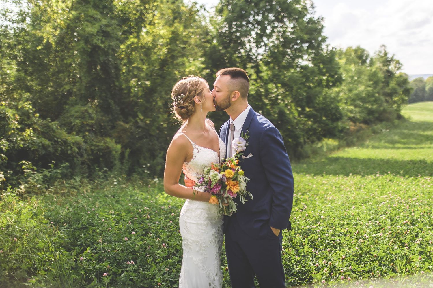 Newlyweds share intimate moments during their wedding photoshoot in a scenic countryside setting.