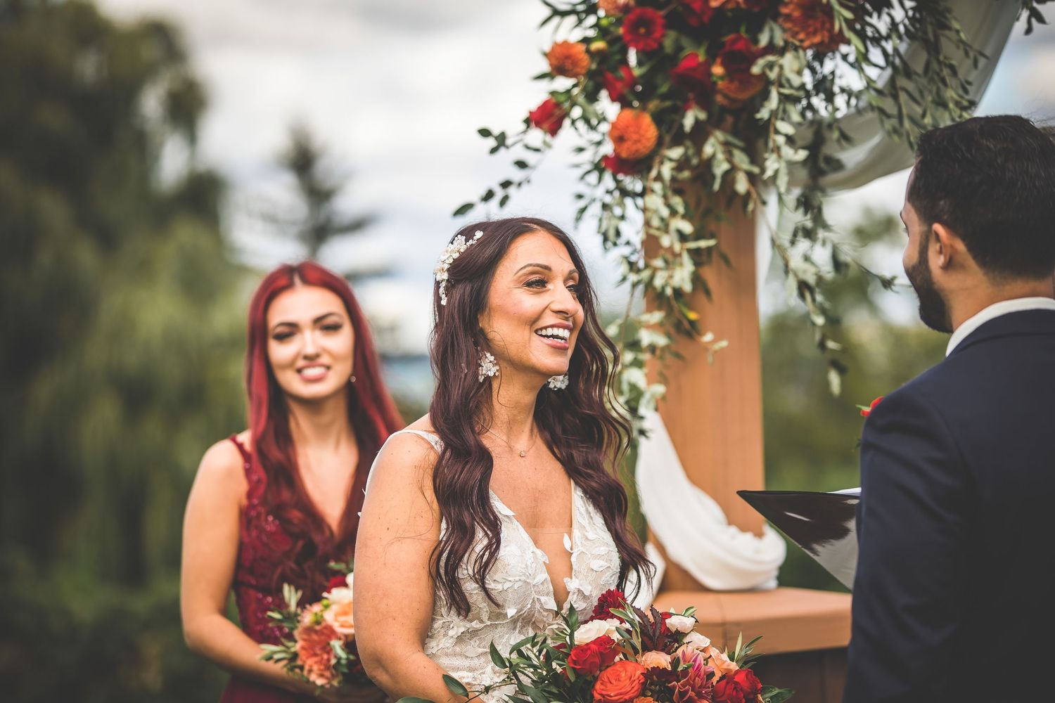 Intimate outdoor wedding ceremony moment under floral arch decoration.