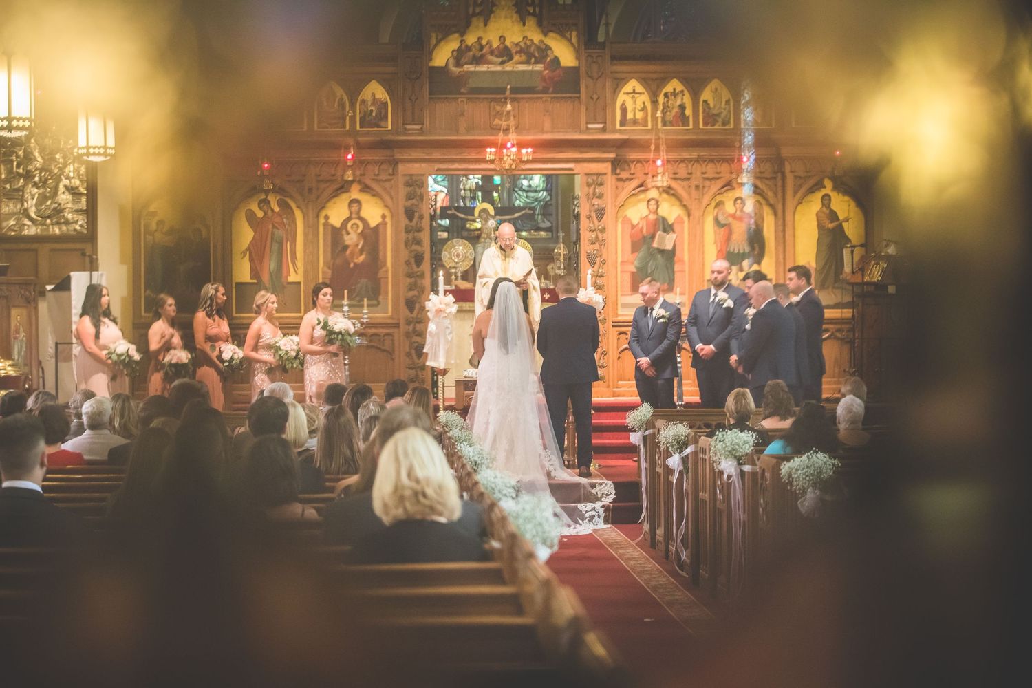 Elegant church interior with golden altar and red carpet during wedding ceremony.
