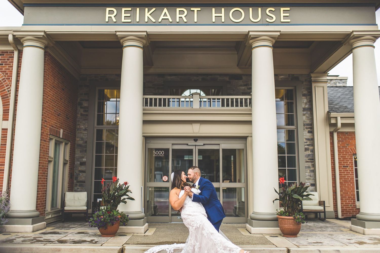 Elegant wedding portrait in front of historic Reikart House with classical columns.