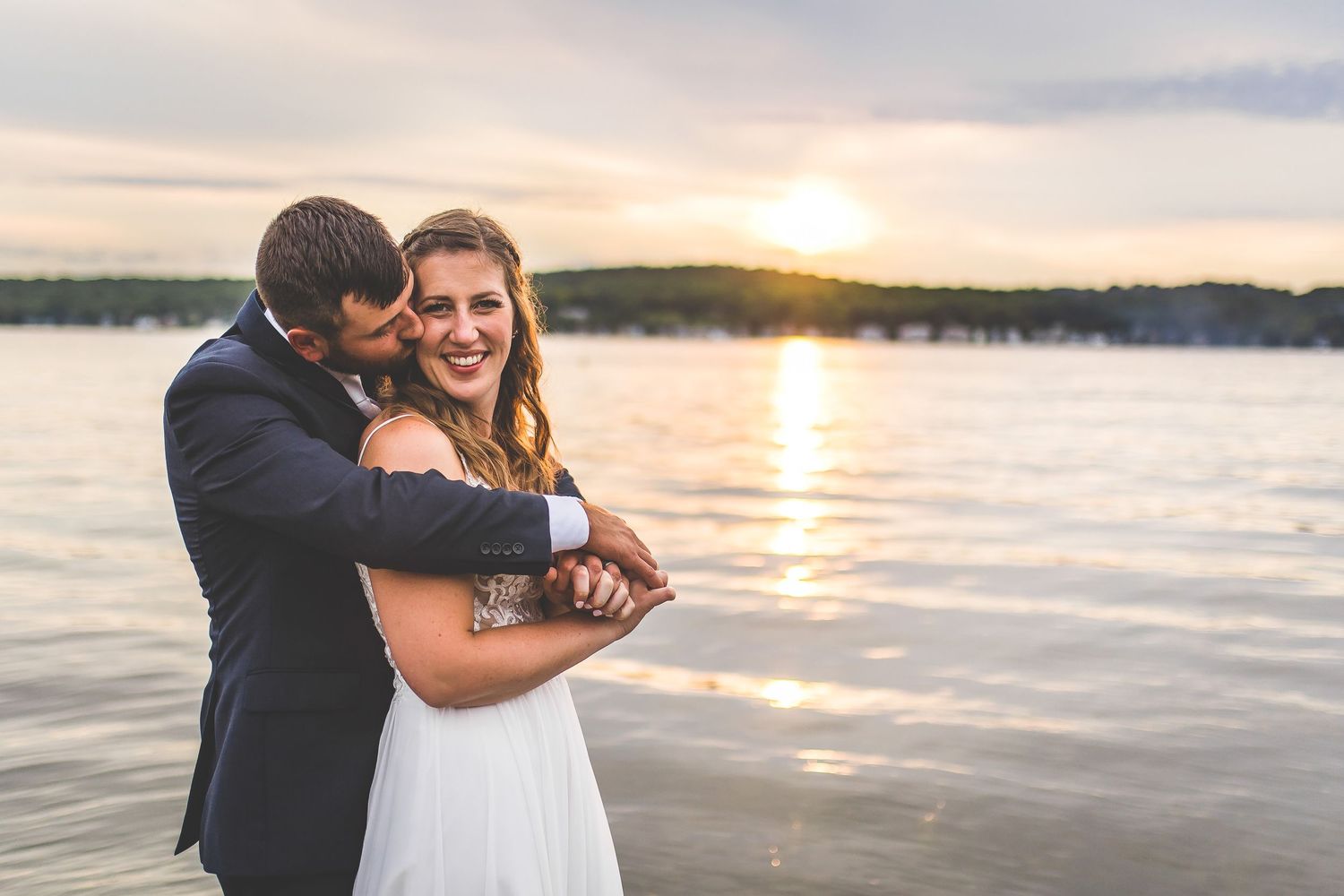 Romantic sunset photoshoot on wooden pier overlooking tranquil lake waters.