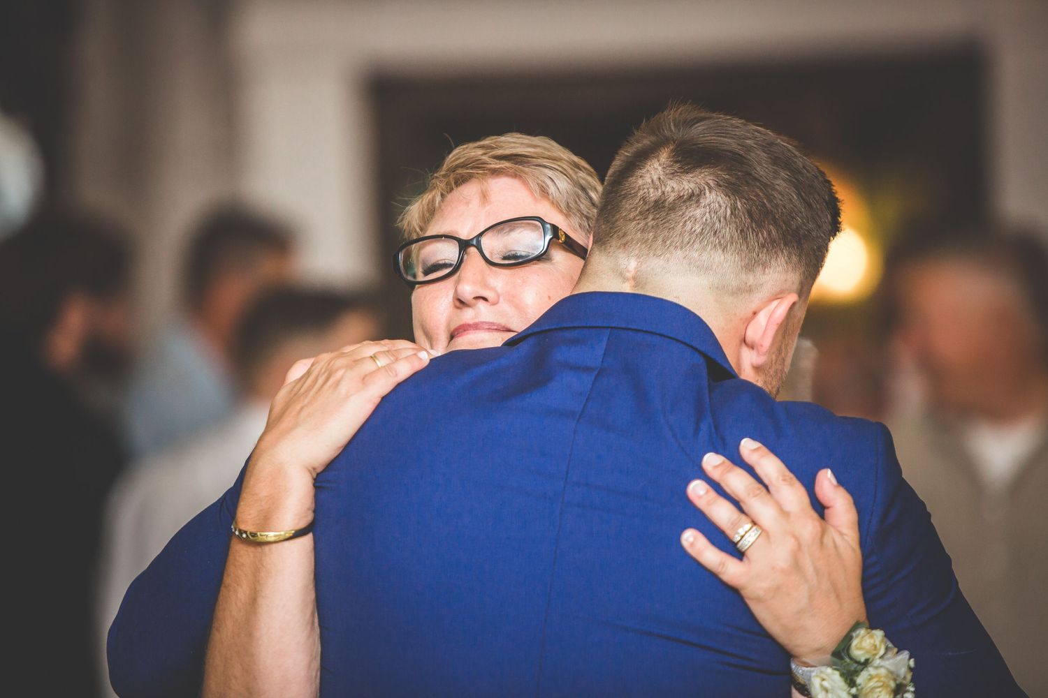 Couples dance together during a wedding reception under ambient lighting.