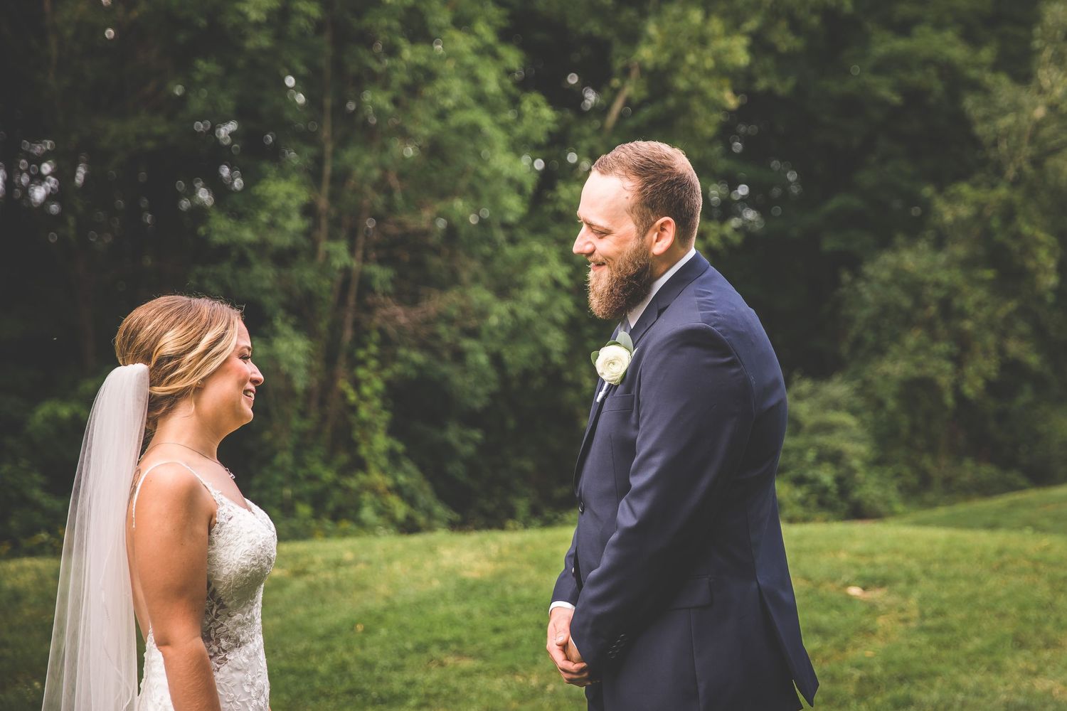 Emotional wedding first look captured in a lush green outdoor setting.