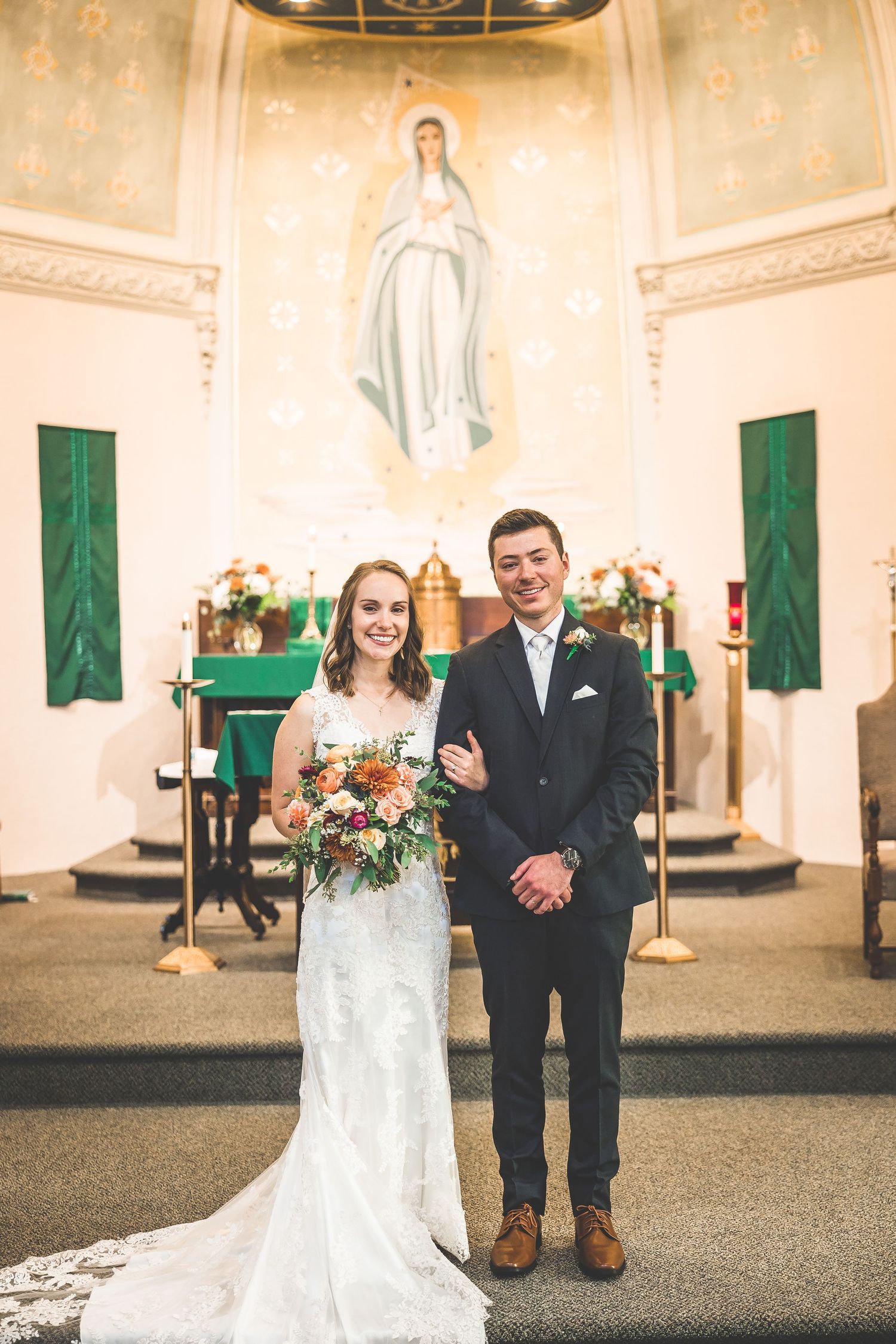 Couple shares candid moments during wedding photos in a church sanctuary with green banners.