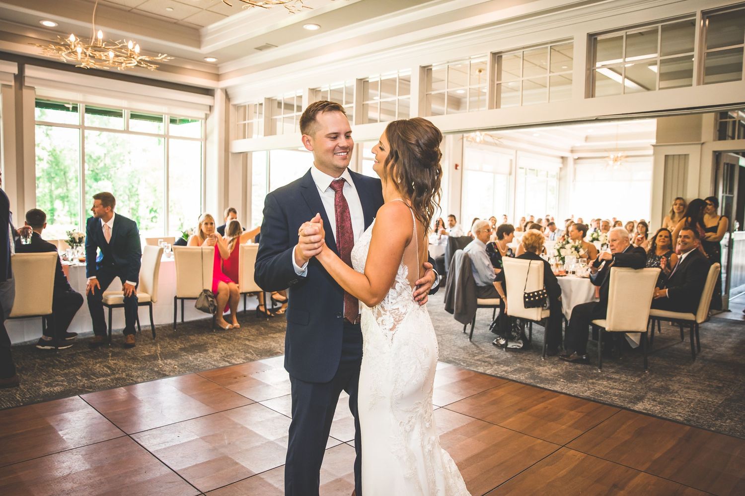 Wedding celebration in an elegant ballroom with high ceilings and large windows.