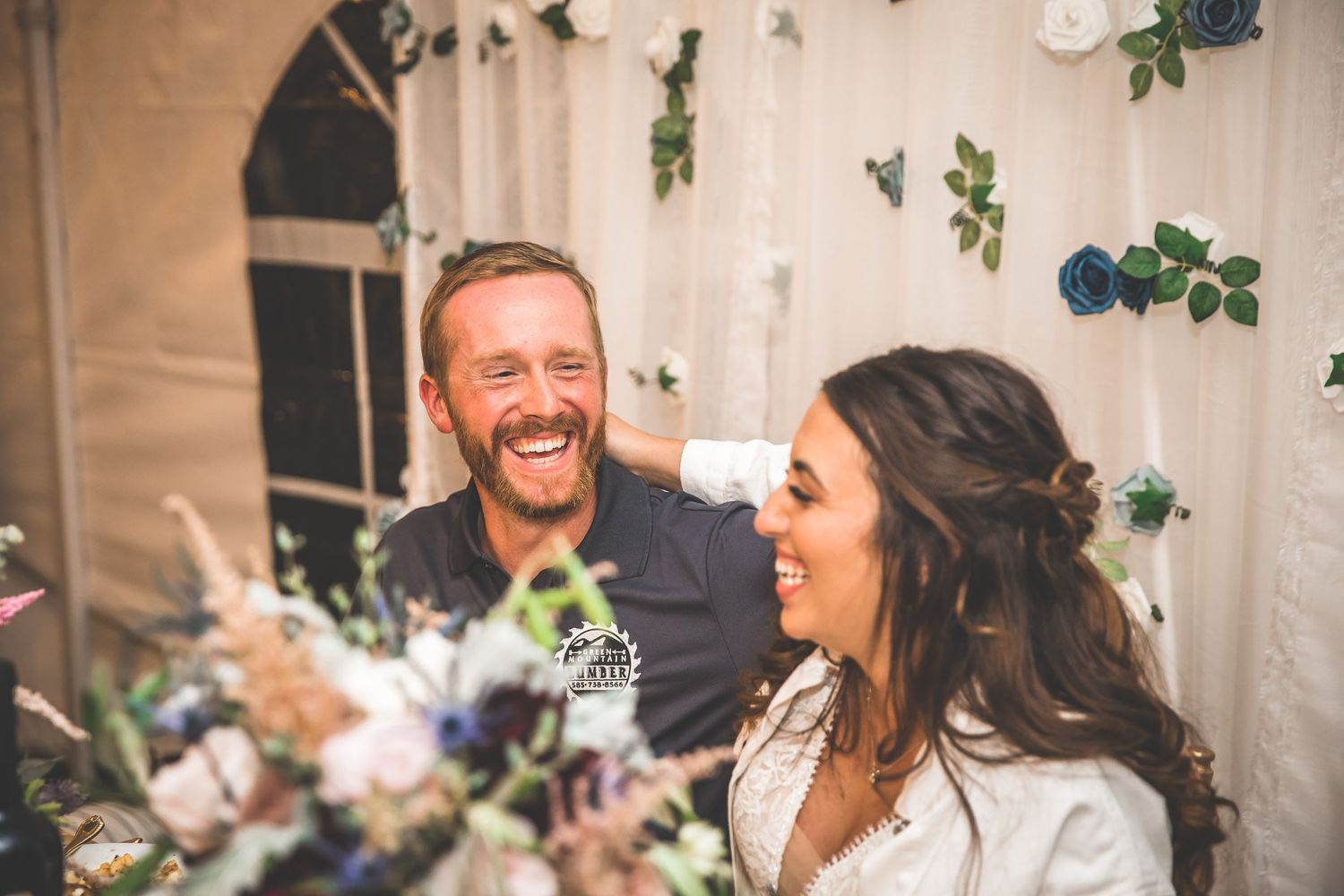 Wedding reception venue decorated with elegant white drapes and hanging greenery.