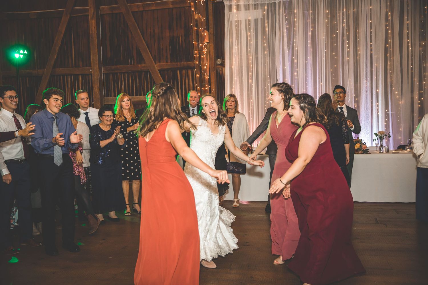 Wedding guests dancing and celebrating on a rustic barn dance floor.