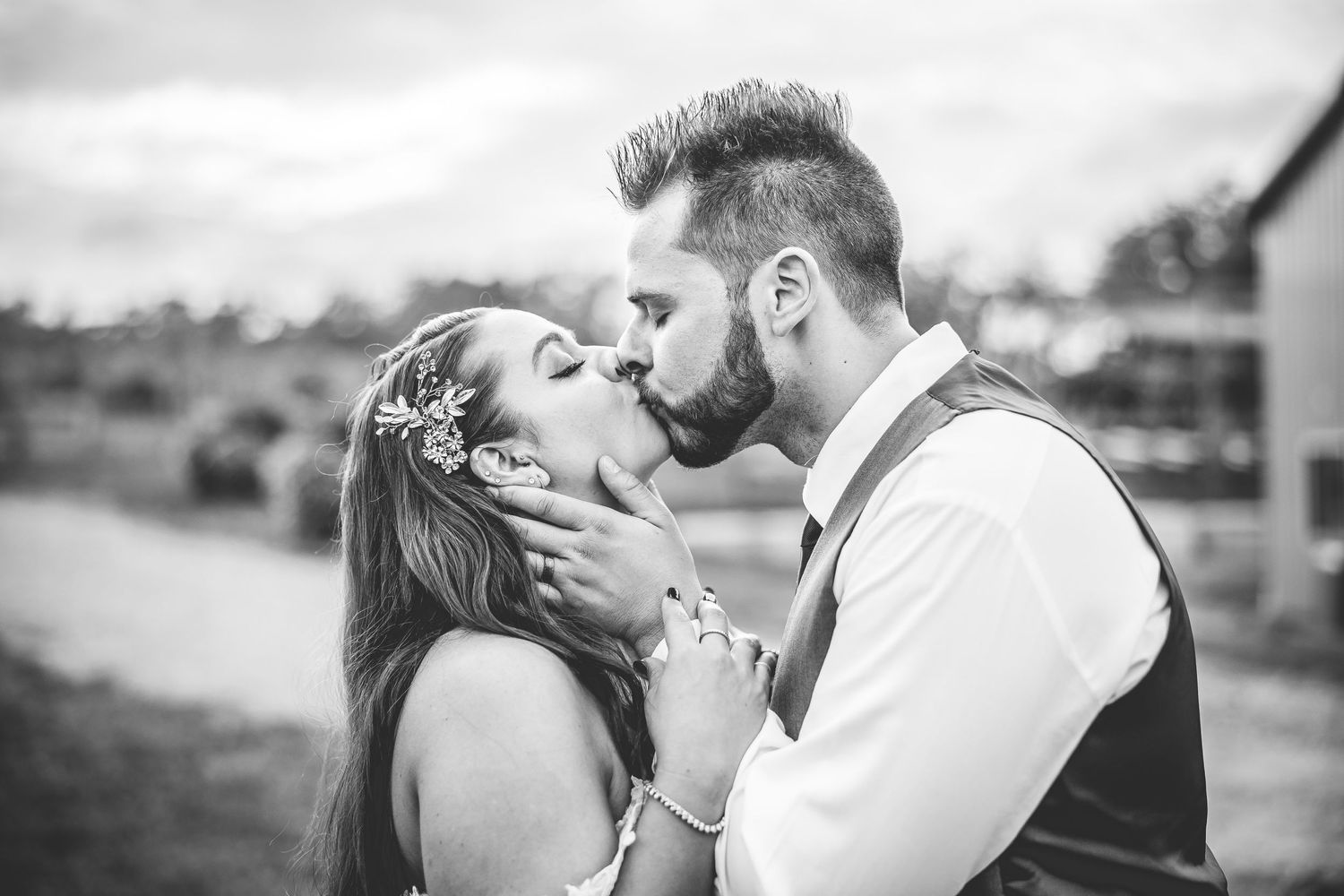 Black and white wedding portrait capturing an intimate moment at sunset.