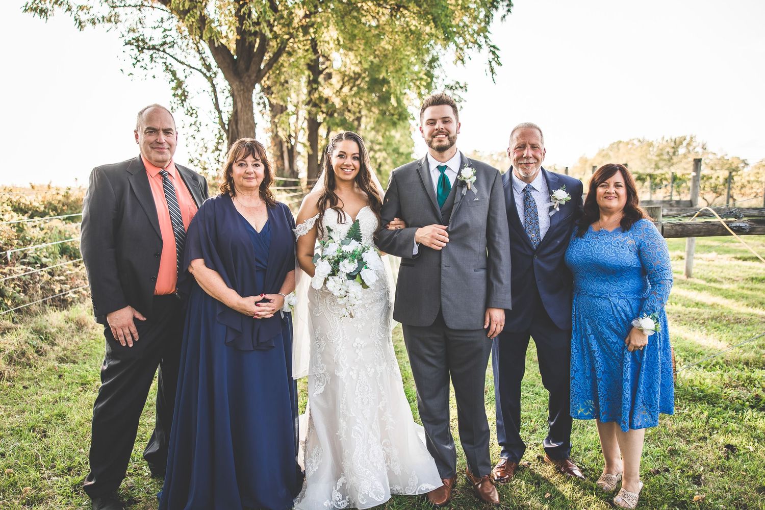Wedding party and family members pose for formal portraits outdoors in blue and purple attire.