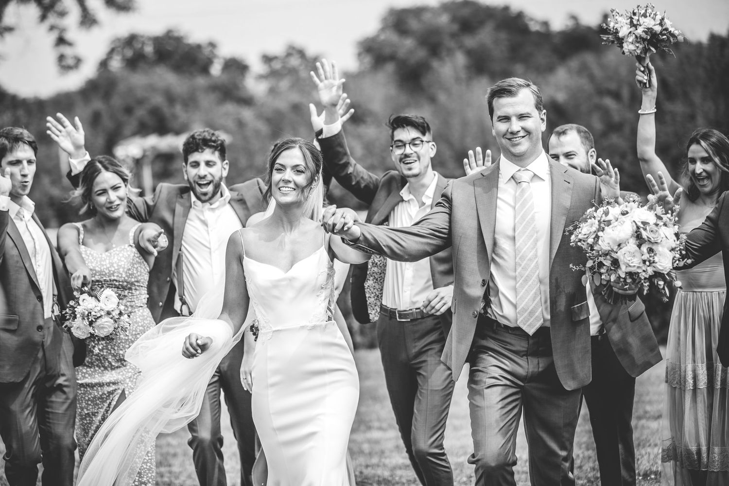 Wedding party celebrates with joyful poses in black and white photography.
