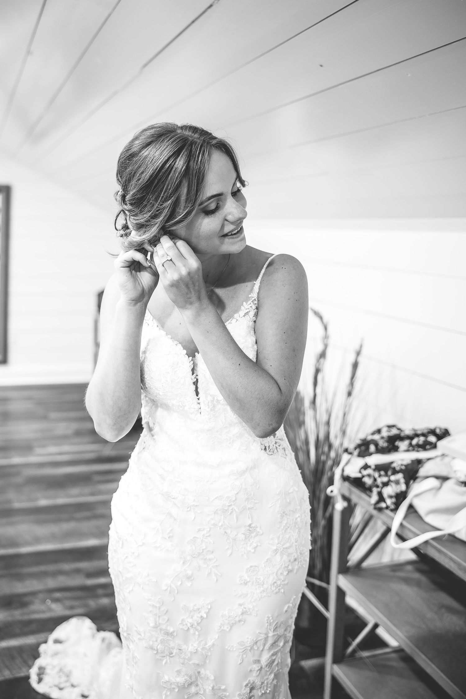 Black and white portrait of bride adjusting her veil in natural window light.