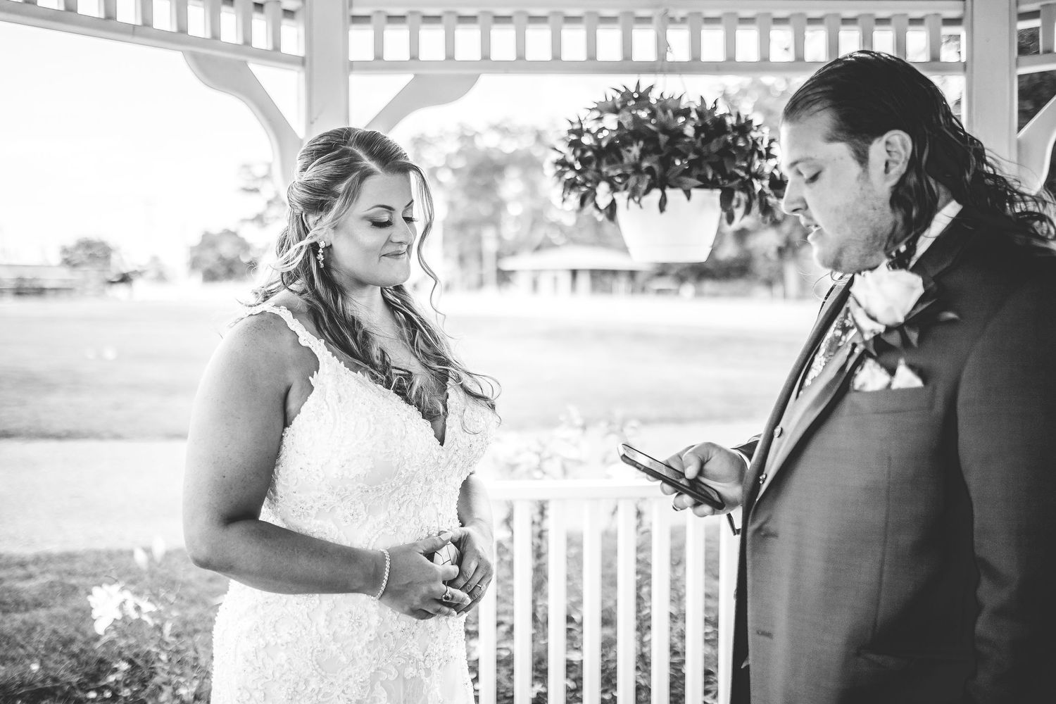 A couple exchanges vows in a white gazebo during an intimate wedding ceremony in black and white.