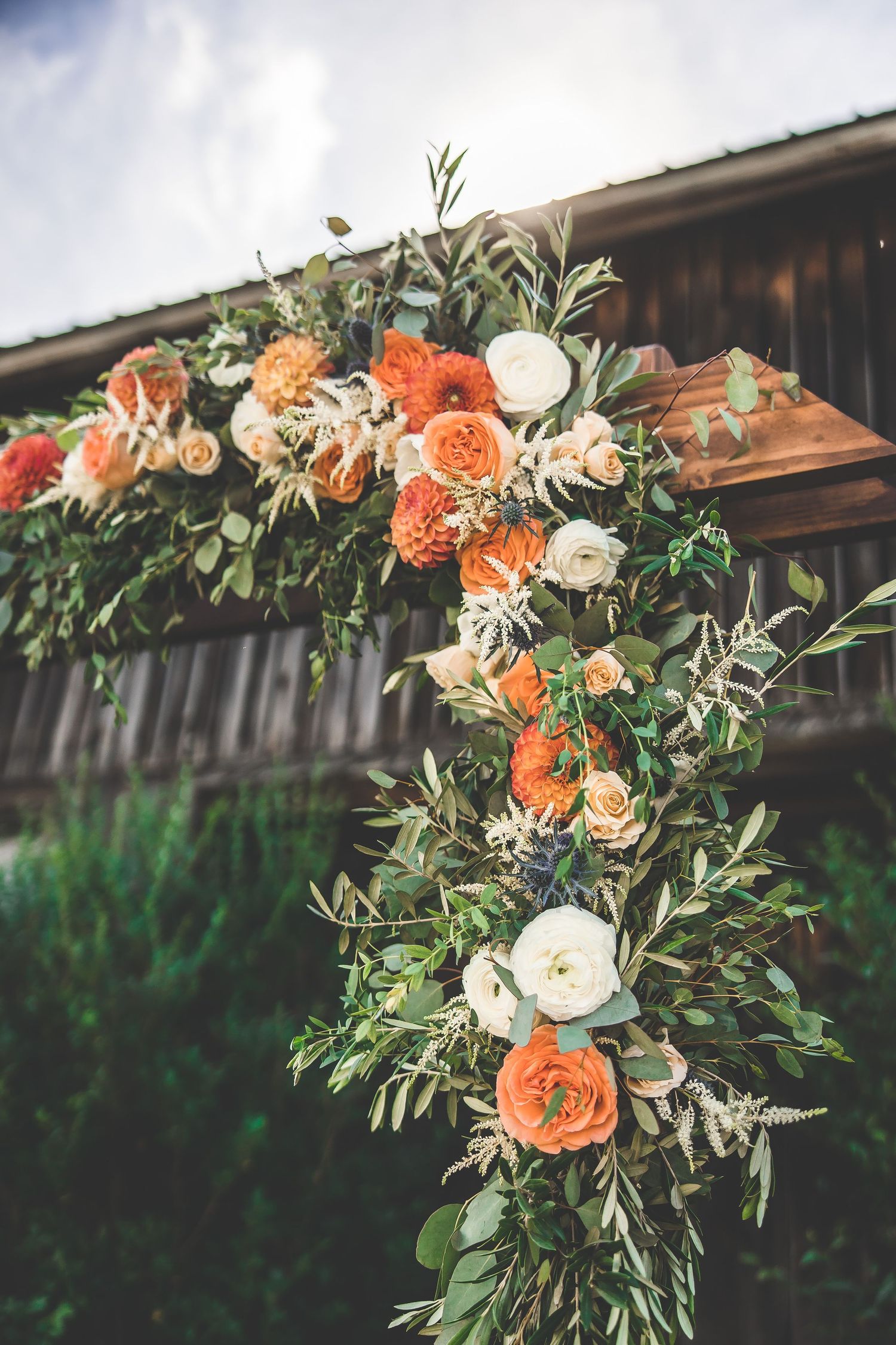 Lush floral arch arrangement featuring peach and white roses with greenery.