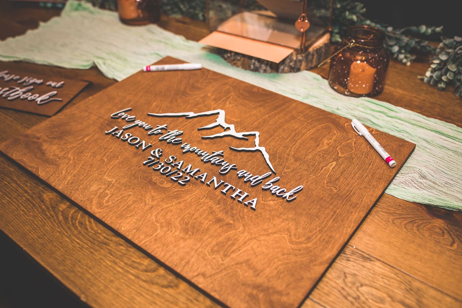Wooden signs with mountain designs and text displayed at wedding venue.