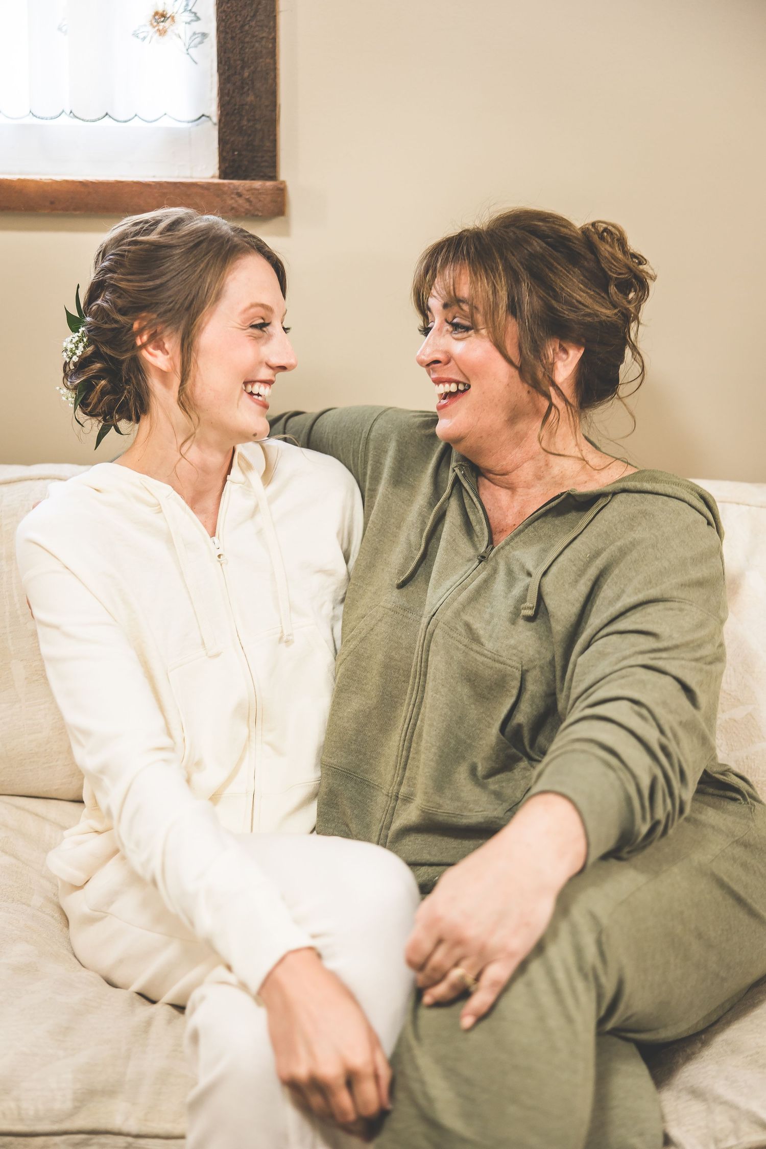 Two people in casual attire share genuine laughter while sitting together on a couch.