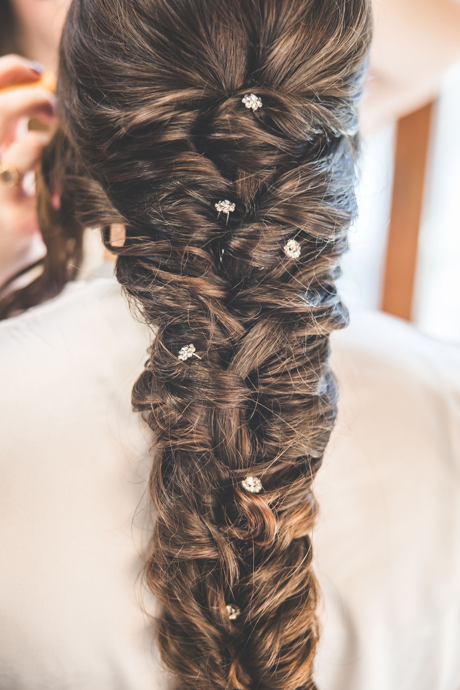 Intricate bridal hairstyle with small crystal accessories woven through braided dark hair.