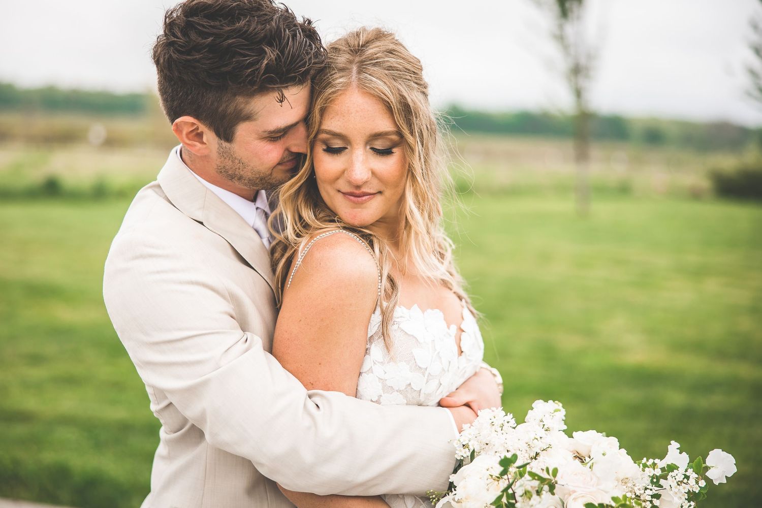 Romantic wedding couple portraits in green countryside setting.