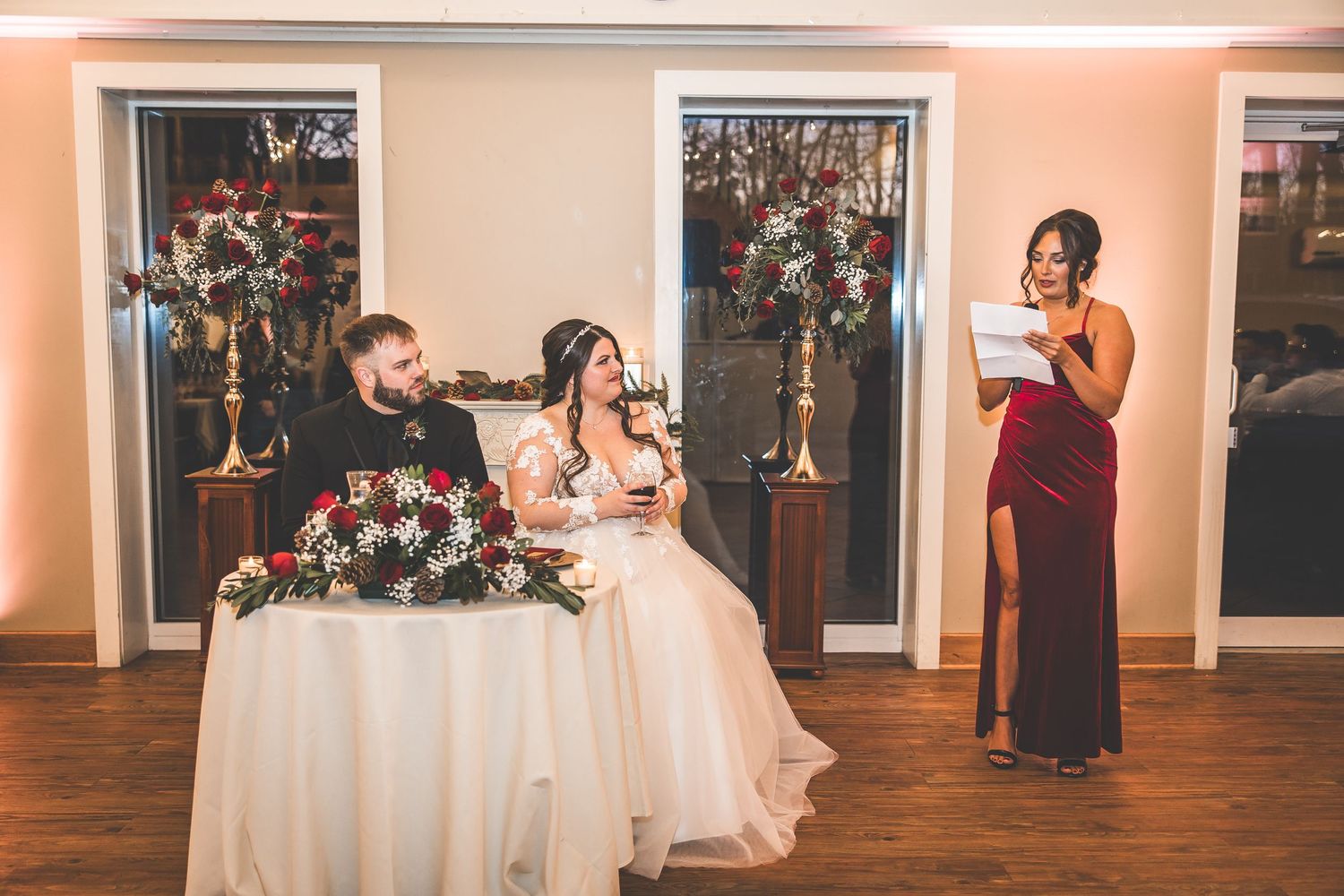 Wedding guests dance and celebrate on a wooden dance floor under warm lighting at an elegant reception venue.