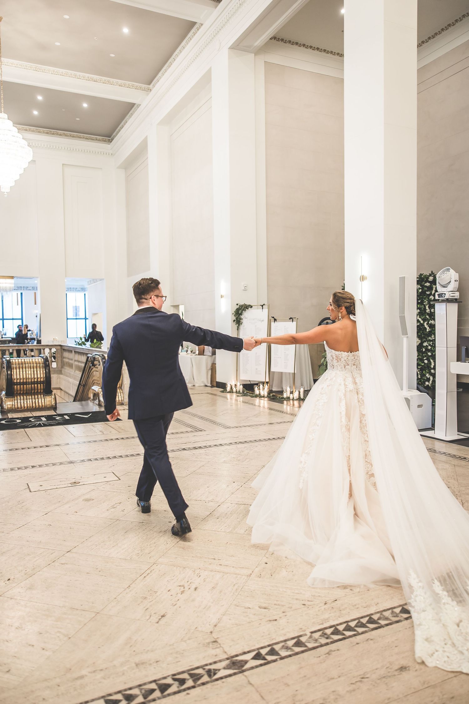 Couple dances in elegant white ballroom with flowing wedding dress twirling during their first dance.