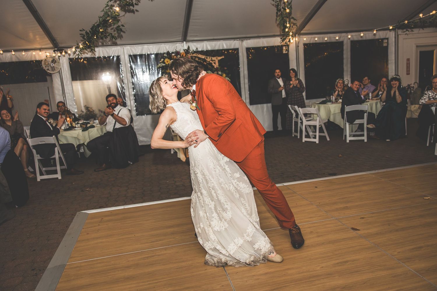 Couples dance together during an evening wedding reception under string lights.