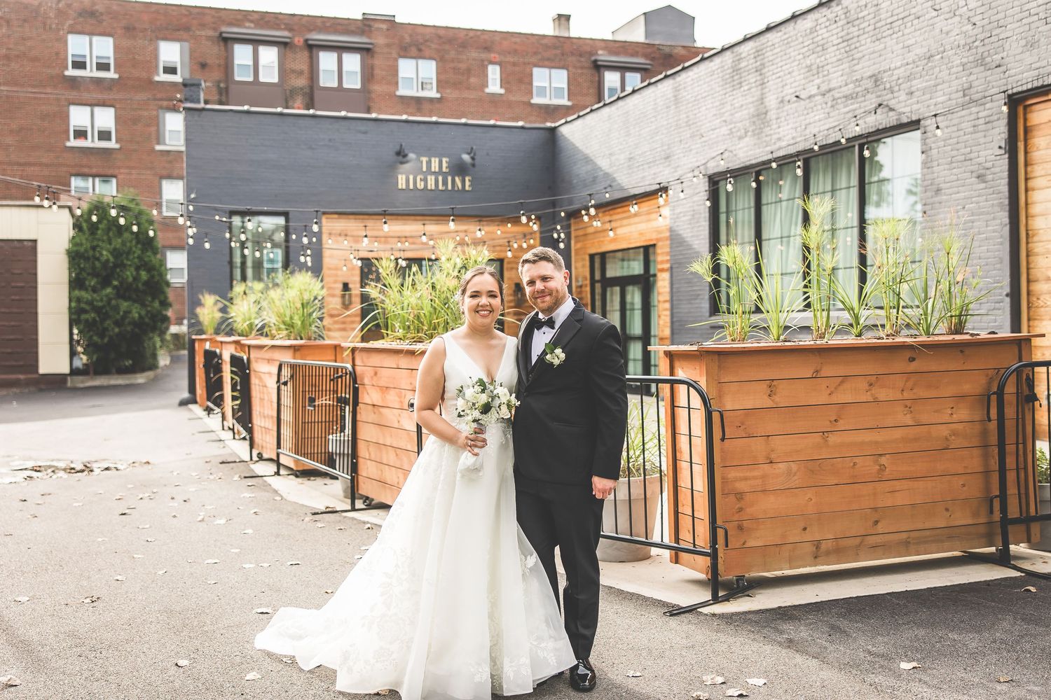 Elegant outdoor wedding venue with wooden paneling and string lights creating a romantic urban atmosphere.
