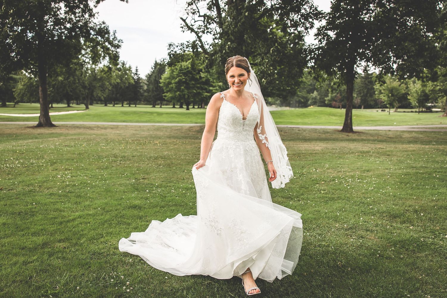 The bride's dress billows elegantly in the breeze during an outdoor wedding photoshoot.
