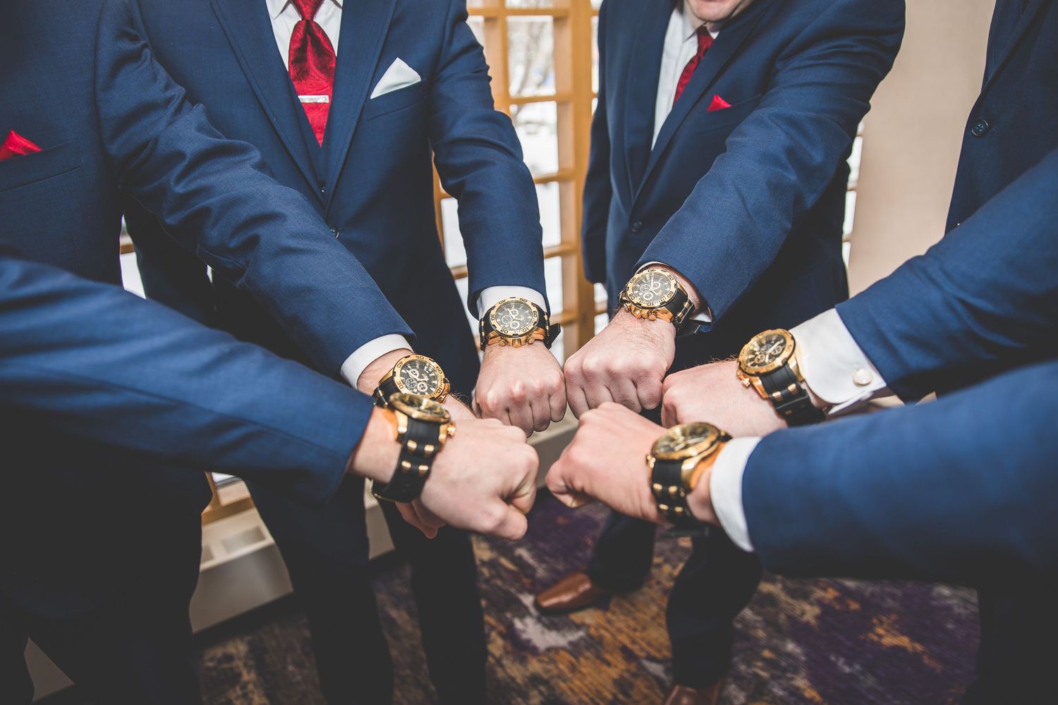 Row of groomsmen in navy suits showing their matching watches.