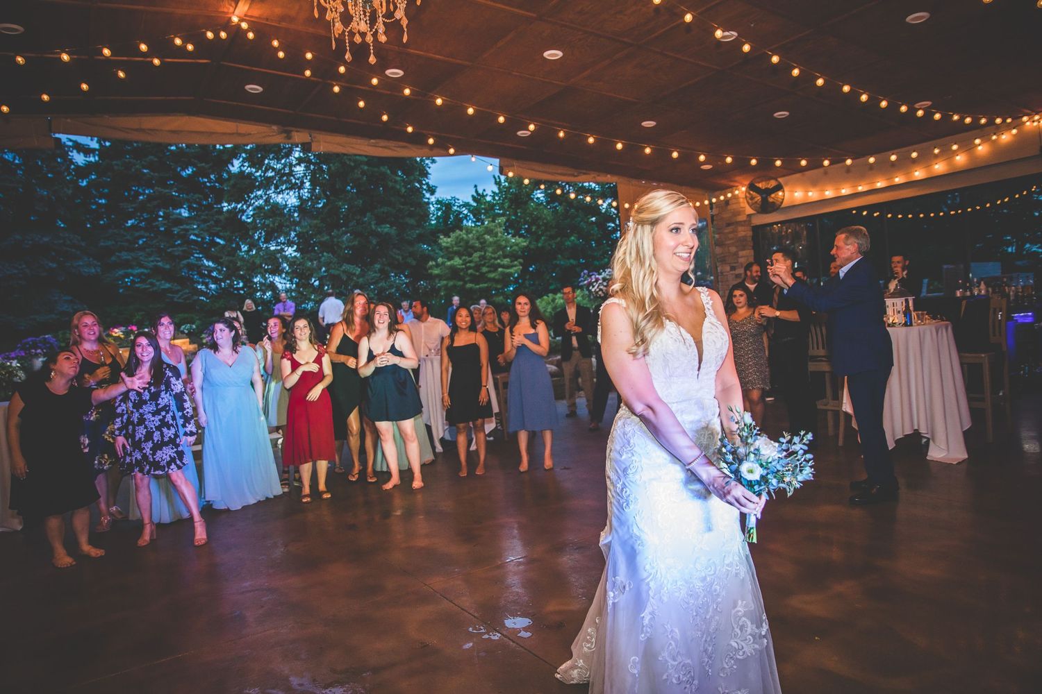 Wedding reception venue decorated with string lights and filled with dancing guests.